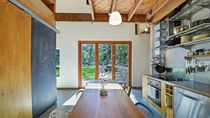 Una cucina moderna con travi in legno, un'ampia finestra e un'area pranzo con tavolo in legno.