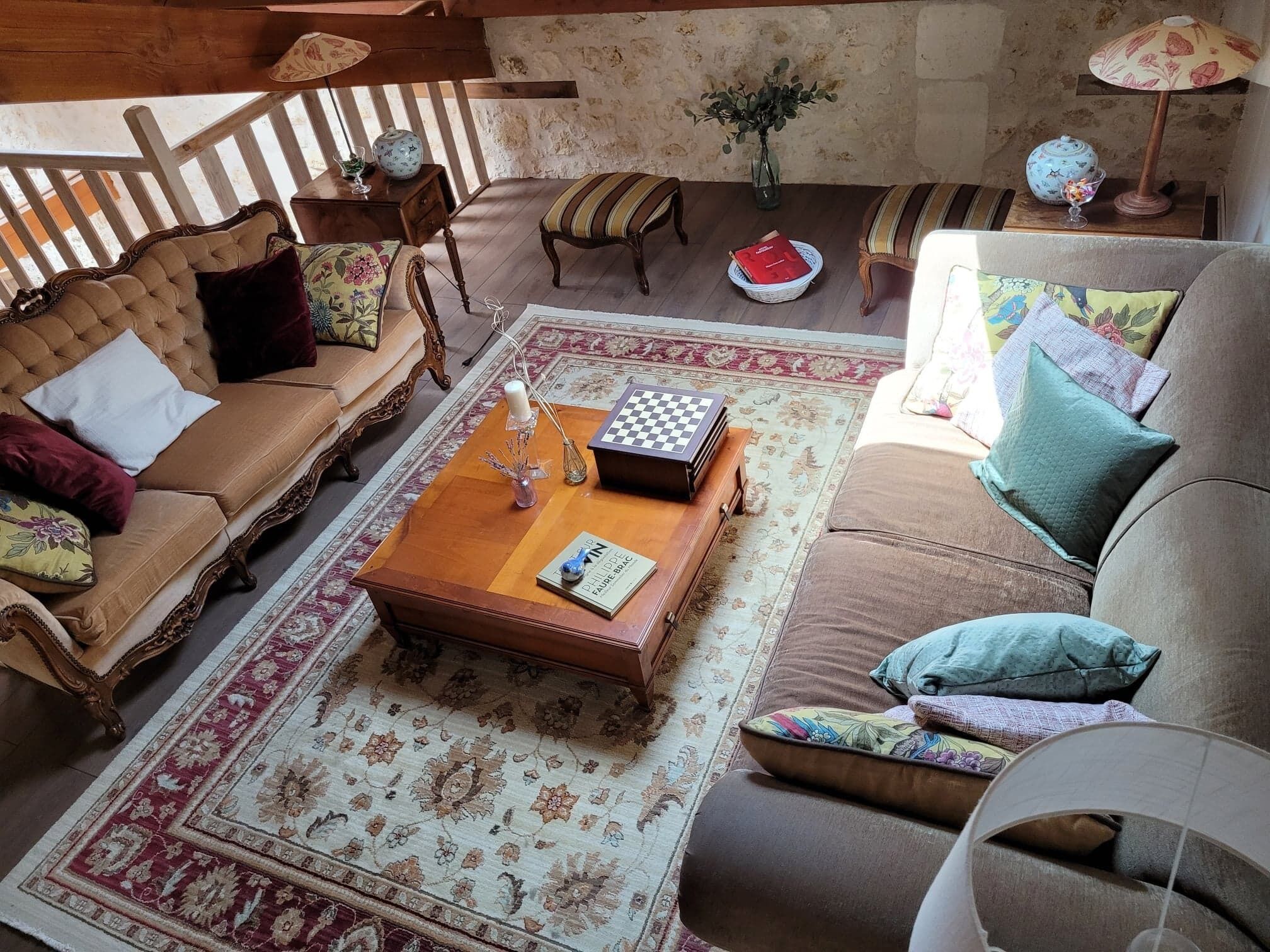 A cozy living room with a wooden coffee table, two sofas, a patterned rug, and a wooden bench.