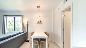 A modern dining area with a white table, wooden chairs, a bench, and a pendant light. - Lovely Studio near Universal Studios (Orlando)
