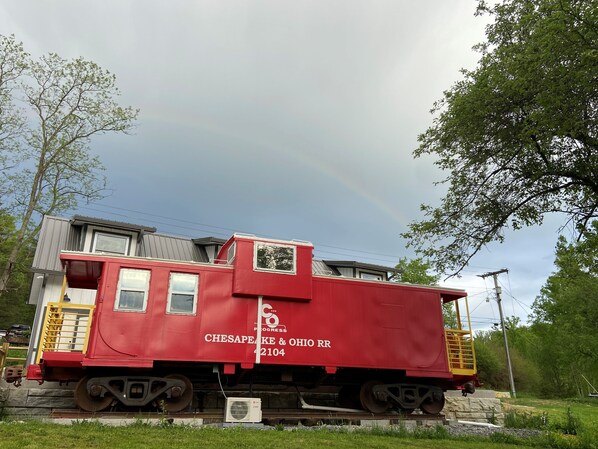 Un wagon de queue rouge portant les inscriptions « Chesapeake & Ohio RR » et « 2104 », garé sur des voies ferrées, avec une maison en arrière-plan.