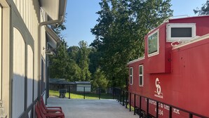A covered outdoor area with red plastic chairs, a red building with a logo, and a clear sky.