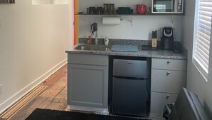 A compact kitchen with a built-in dishwasher, a microwave, and a coffee maker.