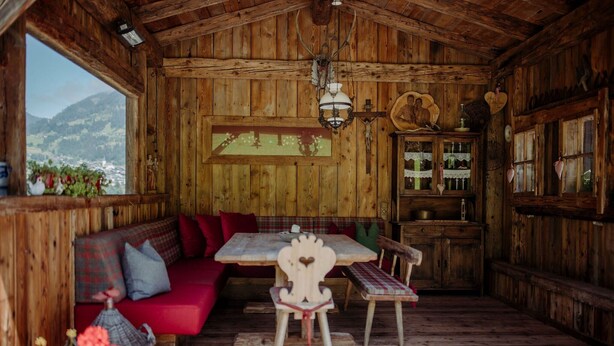 Une cabane en bois avec un banc, une table et des chaises, tous en bois.