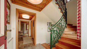 Un escalier avec des marches en bois et des rampes en métal vert, menant à l’étage supérieur.