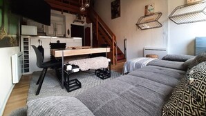 Ett mysigt vardagsrum med en soffa, ett matbord och en trappa.