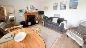 A cozy living room with a fireplace, a dining table, and a sofa. - Glenbeigh Holiday Cottage - Tigin Mamo (Glenbeigh)