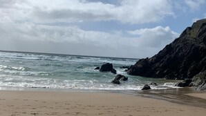 A sandy beach with footprints leading to the water, a rocky cliff, and a partly cloudy sky. - Glenbeigh Holiday Cottage - Tigin Mamo (Glenbeigh)