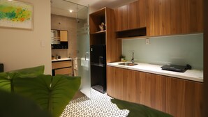 Une cuisine moderne avec des meubles en bois, un réfrigérateur noir et un ordinateur portable posé sur le plan de travail.