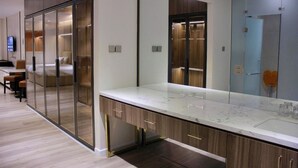 Une chambre d’hôtel moderne dotée d’un grand miroir, d’un comptoir en marbre et d’une armoire avec des portes coulissantes.