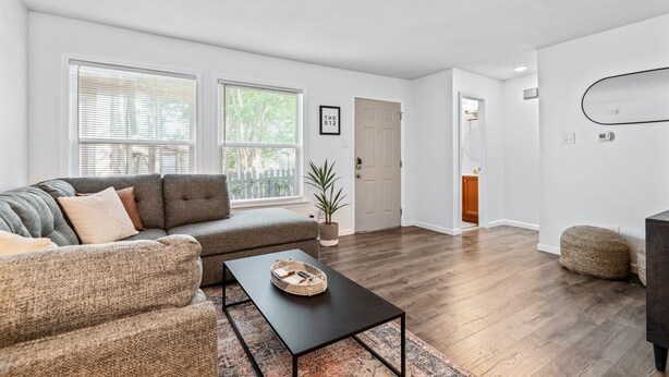 Un salon moderne avec un canapé d’angle, une table basse et une grande fenêtre.