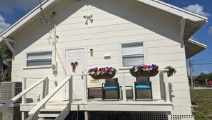 Une maison blanche avec un porche, une petite fenêtre et une porte décorée d’un motif de papillon.