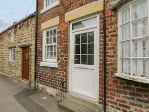 A brick house with a white front door, a window with shutters, and a number '83' on the wall. - Ducky's (Pickering)