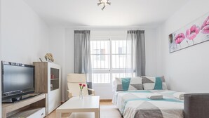 A modern living room with a flat-screen TV, a white table, a sofa, and a bed. - High quality apartment 1 bedroom, 1 bathroom La Algaba (Algaba)