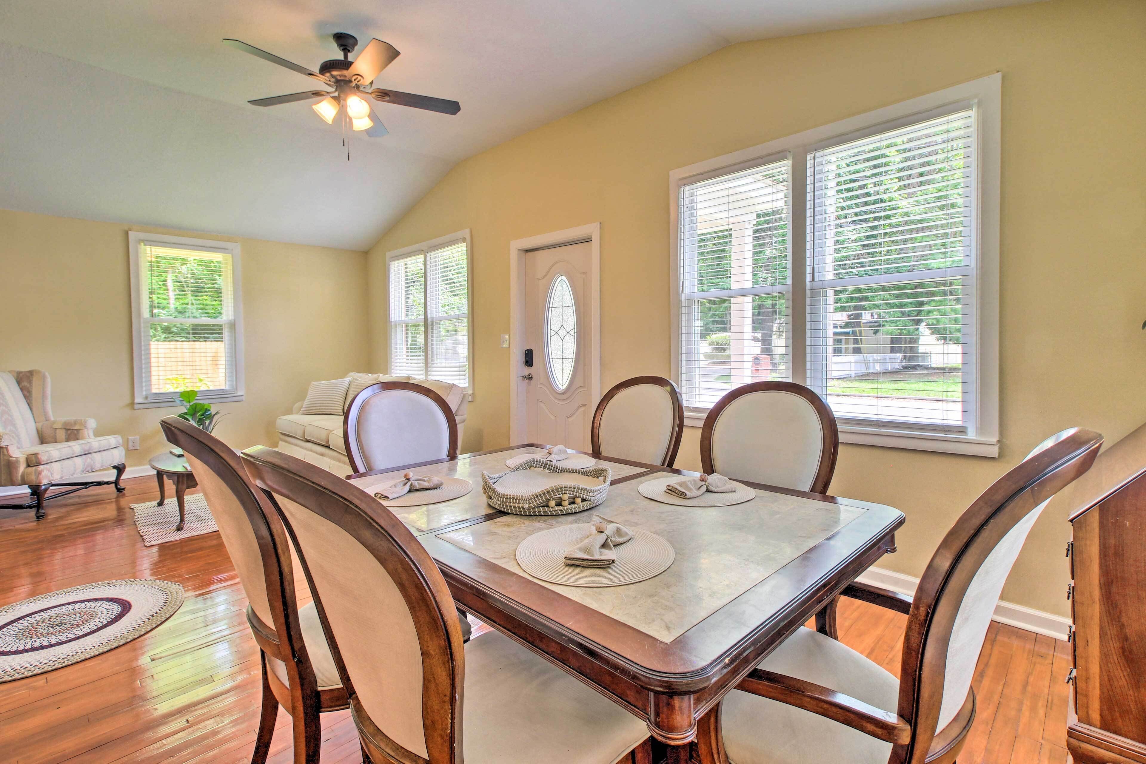 Un coin repas avec une table en bois, six chaises et un ventilateur de plafond.