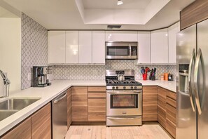Enjoy cooking in this well-equipped kitchen with stainless steel appliances, wooden cabinetry, and a clean countertop.