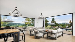 Un vaste espace intérieur doté d’une piscine, d’un coin salon extérieur et de grandes fenêtres offrant une vue panoramique.