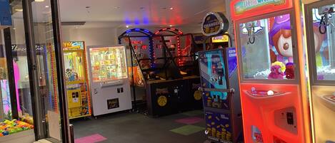 A variety of arcade games in a brightly lit indoor space with colorful floor tiles.
