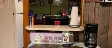 A kitchen with a rustic wooden cabinet, a coffee maker, and a refrigerator.