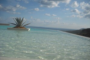 A clear pool with a plant in the center, surrounded by a clear sky and distant mountains. - Masseria del Piano (Campofelice di Roccella)
