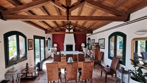 A spacious dining area with a high wooden ceiling, a fireplace, and a bookshelf filled with books. - Masseria del Piano (Campofelice di Roccella)