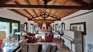 A spacious living area with a high wooden ceiling, comfortable seating, a piano, and a view of the outdoors. - Masseria del Piano (Campofelice di Roccella)