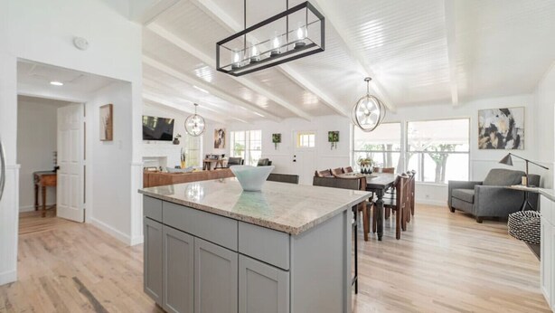 A spacious kitchen with a large island, wooden flooring, and pendant lighting. - Remodeled Lakefront! Private beach, toys & hot tub (Little Elm)