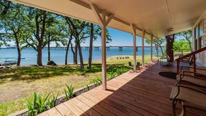 A covered wooden deck with a view of a lake and a bridge. - Remodeled Lakefront! Private beach, toys & hot tub (Little Elm)