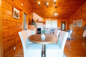 Cozy cabin interior with a round table, upholstered chairs, and a stone fireplace.