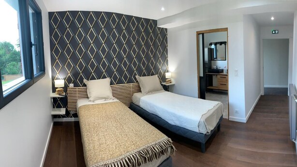 A modern bedroom with two beds, a large window, a mirror, and a walk-in closet. - Appartement AU Coeur DU Pays Basque (Urrugne)