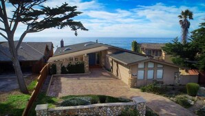 A coastal property with a stone driveway, a covered patio, and a view of the ocean.