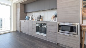 Une cuisine moderne avec des meubles de couleur grise, un four encastré, un four à micro-ondes et une machine à café.