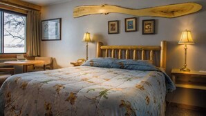 A bedroom with a bed, two bedside lamps, a wooden headboard, a desk, and a chair.