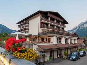 A multi-story hotel with balconies, outdoor seating, and mountain views.