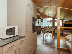 A modern kitchen with a microwave, cabinets, and a dining area with a table and chairs.