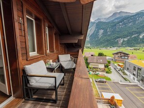 A wooden balcony with two chairs and a table, overlooking a mountain landscape. - Brienz Sunset by Interhome (Brienz)