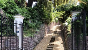 Un étroit sentier de pierre, bordé de grilles en métal noir, mène à un bâtiment.