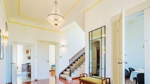 Un vaste espace de vie doté d’un plancher en bois franc, d’un escalier avec une rampe en métal et d’un grand miroir mural.