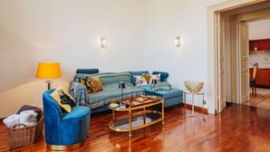Un salon avec un canapé bleu, une table basse ronde et une lampe. On y trouve un panier en osier et une petite table sur laquelle est posé un objet décoratif.