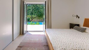 Une chambre moderne avec un grand lit, une vue sur une piscine et un luminaire au plafond.