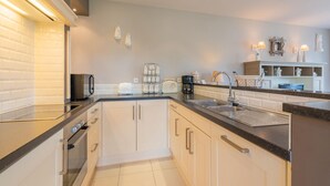 A modern kitchen with white cabinets, black countertops, and stainless steel appliances. - Inviting holiday home in Nieuwpoort with garden (Nieuwpoort)