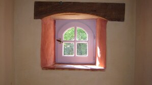 Uma pequena janela com moldura de madeira e uma porta, em uma parede lisa.
