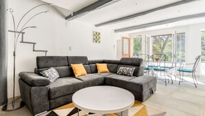 A modern living room with a grey sectional sofa, a white coffee table, and a geometric patterned rug.