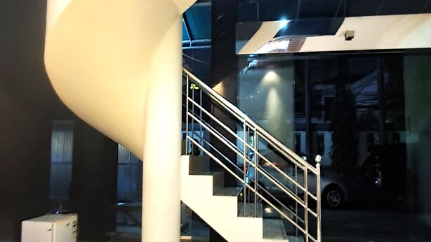 A modern building with a curved white structure, a glass staircase, and a security camera.