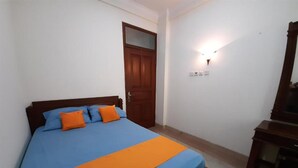 A bedroom with a bed, a wooden door, and a wall-mounted light fixture.