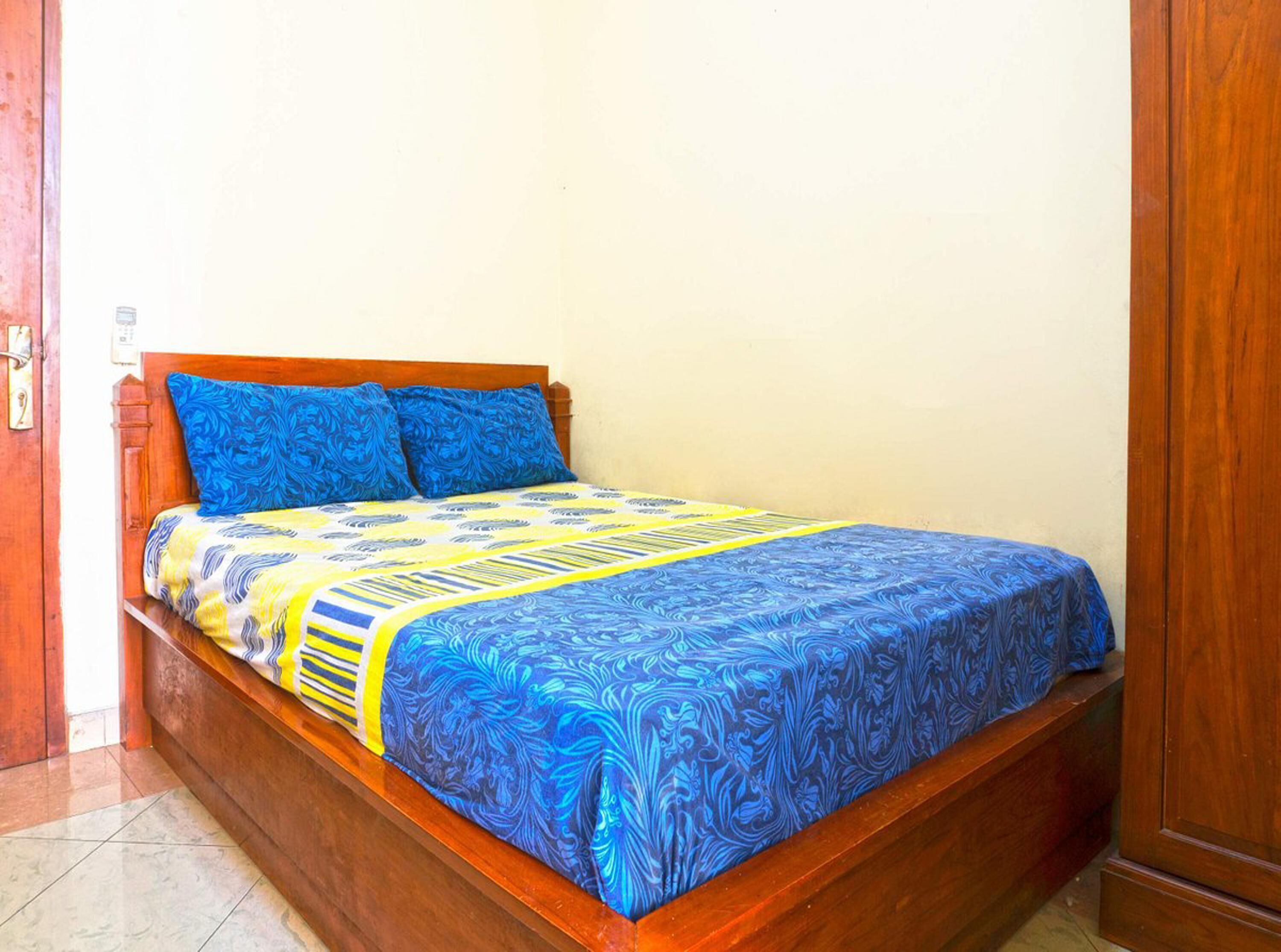 A single bed with a wooden frame and a patterned bedspread.