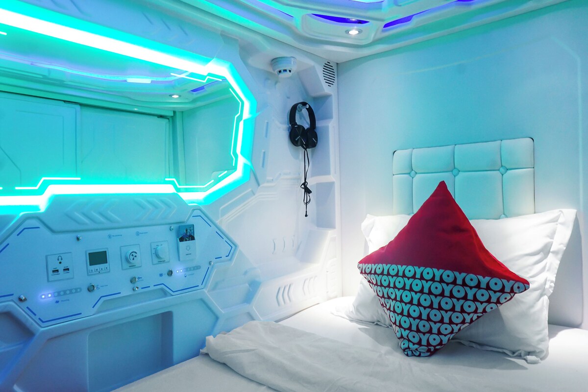 A modern bedroom with a control panel, a bed with a red and white pillow, and a headboard.