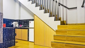 A modern kitchen with a wooden staircase and a view of the living area. - Hotel O Fiducia Capsule Hotel (Jakarta)