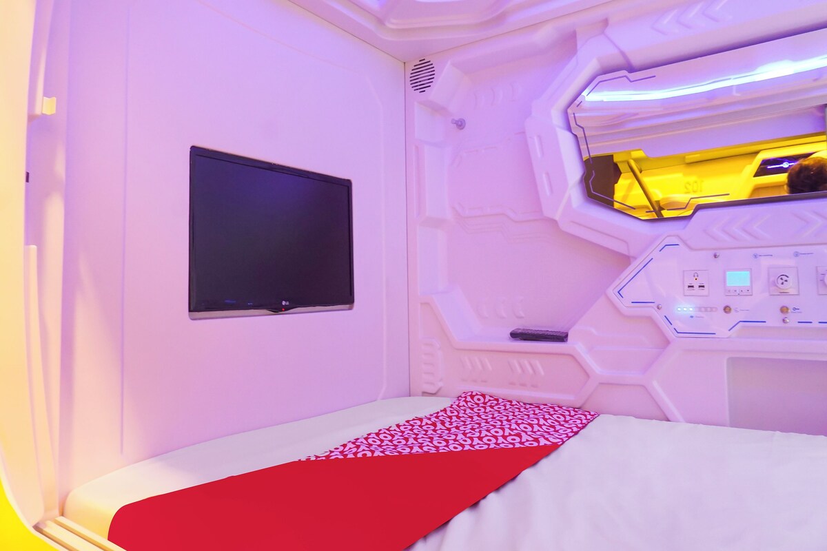 Una habitación futurista con una cama, un televisor de pantalla plana y un panel de control.