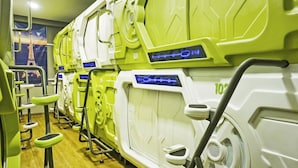A row of gym equipment with digital displays, a wooden floor, and a poster of the Eiffel Tower. - Hotel O Fiducia Capsule Hotel (Jakarta)