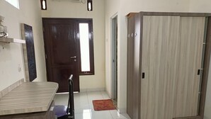 A room with a wooden desk, a chair, a wardrobe, and a door.